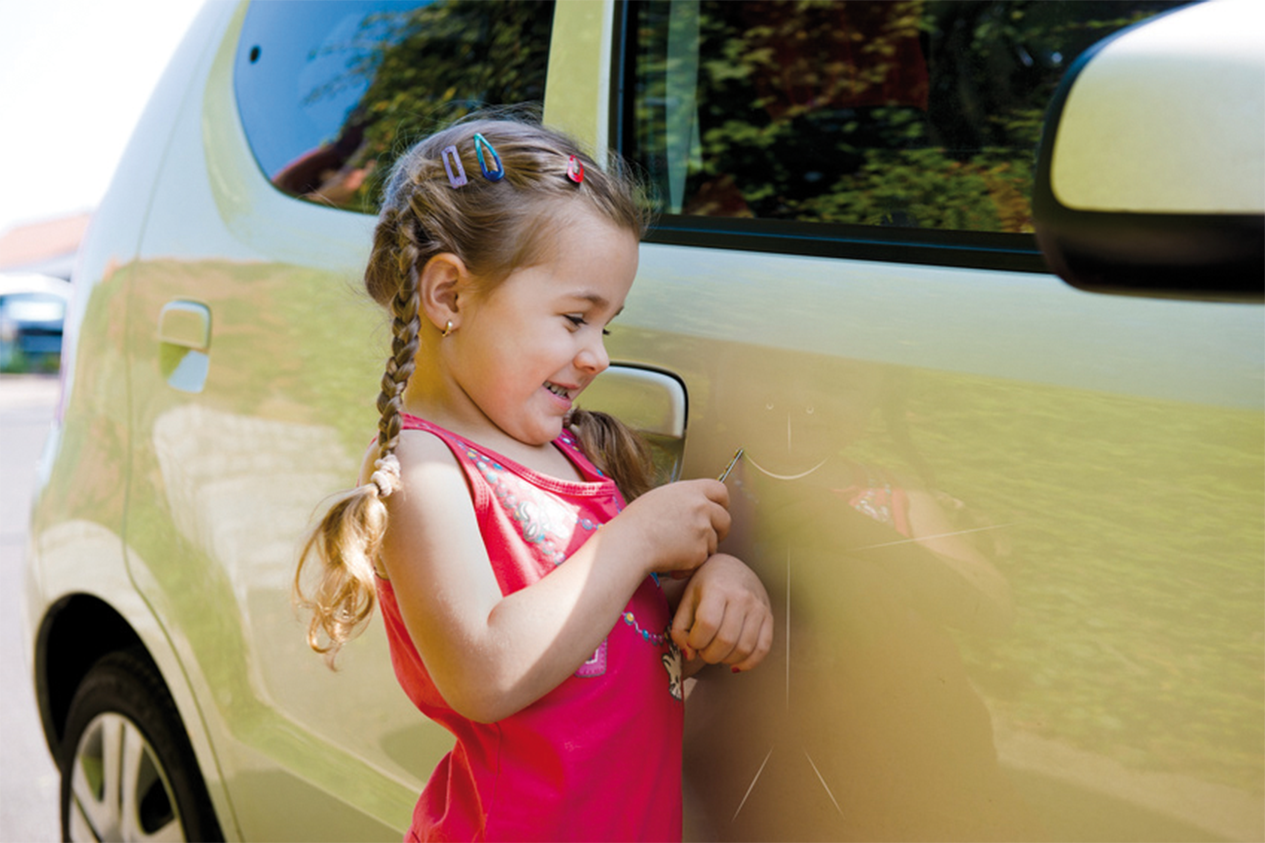 Kleines Mädchen macht mit Schraubenschlüssel einen Strichmännchen in den Autolack.